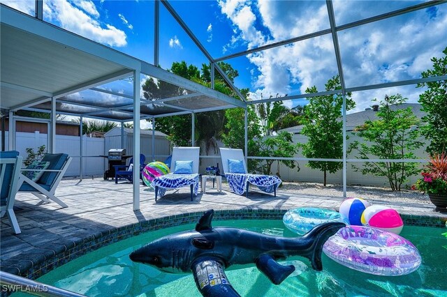 view of swimming pool with a patio, glass enclosure, a fenced backyard, an outbuilding, and a storage unit