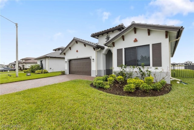 mediterranean / spanish home with a garage, decorative driveway, a front yard, and stucco siding