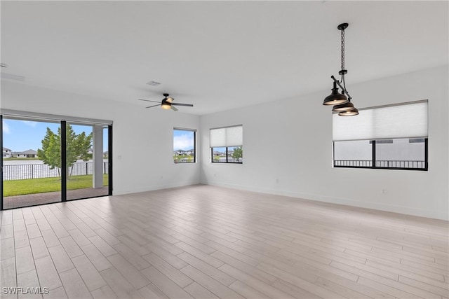 spare room featuring a ceiling fan, light wood-type flooring, and baseboards