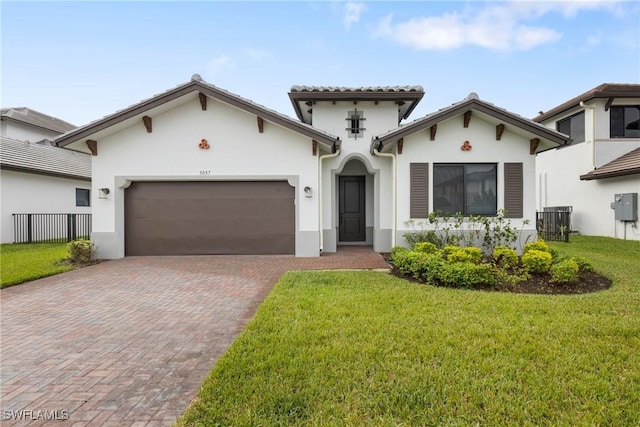 mediterranean / spanish house featuring a garage, a front yard, decorative driveway, and stucco siding