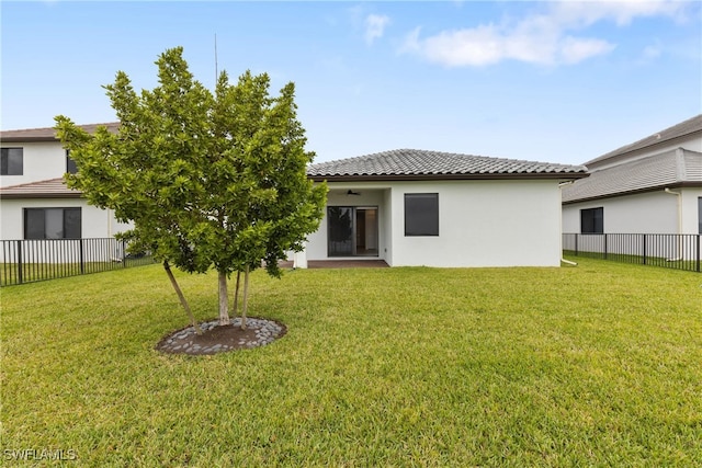 back of property featuring a tile roof, a yard, fence, and stucco siding