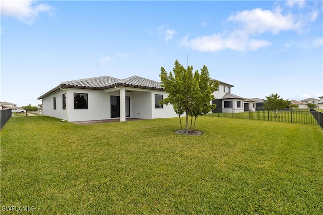 rear view of property with a yard, a tile roof, a fenced backyard, and ceiling fan