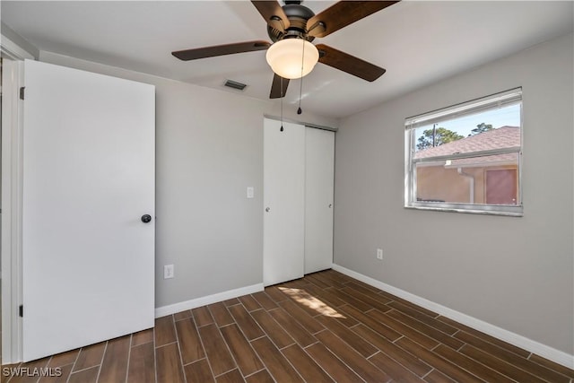 unfurnished bedroom with wood finish floors, a closet, visible vents, a ceiling fan, and baseboards