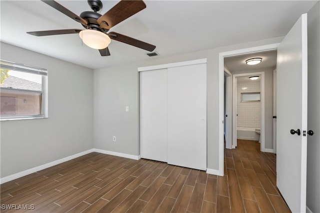 unfurnished bedroom with baseboards, visible vents, dark wood-style floors, ceiling fan, and a closet