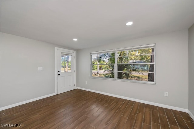 spare room with baseboards, dark wood-type flooring, and recessed lighting