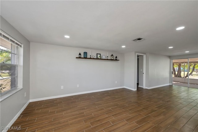 unfurnished room with baseboards, visible vents, dark wood finished floors, and recessed lighting