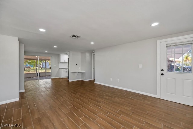 unfurnished living room with baseboards, dark wood-style flooring, visible vents, and recessed lighting