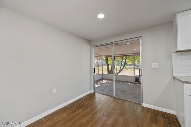 unfurnished dining area featuring a sunroom, baseboards, dark wood finished floors, and recessed lighting