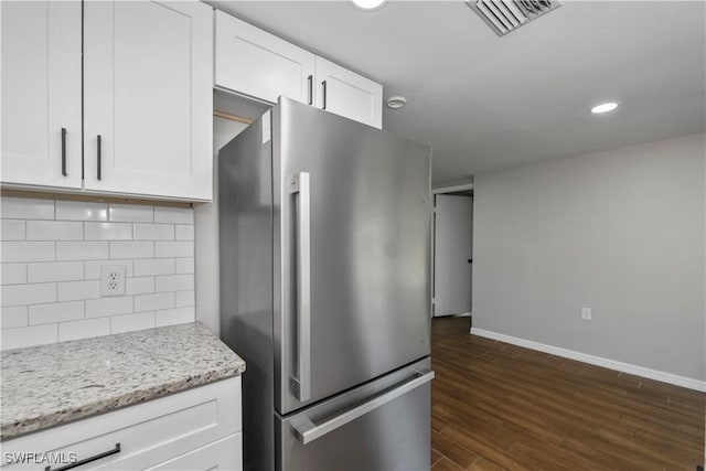 kitchen featuring dark wood-style flooring, visible vents, backsplash, freestanding refrigerator, and white cabinets