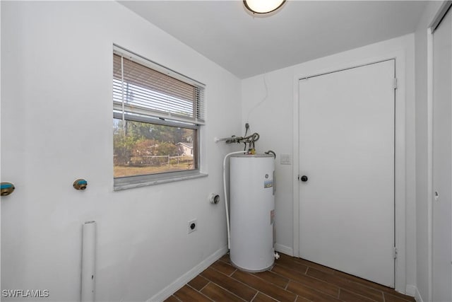 laundry area with wood tiled floor, electric water heater, hookup for an electric dryer, laundry area, and baseboards