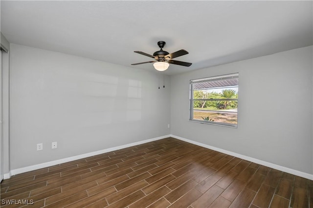 unfurnished room with dark wood-style floors, ceiling fan, and baseboards