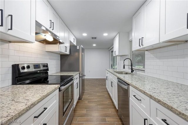 kitchen featuring appliances with stainless steel finishes, white cabinets, a sink, and under cabinet range hood