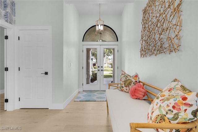 entrance foyer featuring french doors, a high ceiling, baseboards, and wood finished floors