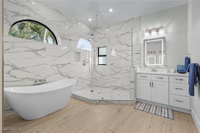 full bath featuring a freestanding bath, a marble finish shower, wood finished floors, and vanity