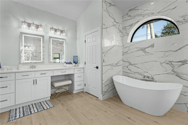 full bath with wood finished floors, a freestanding tub, and vanity