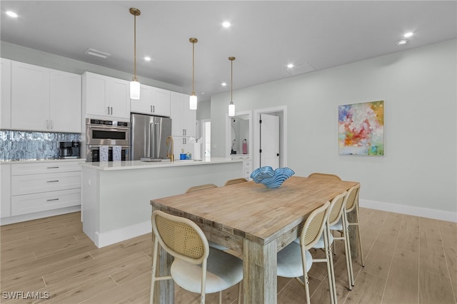 dining space featuring baseboards, light wood-style flooring, and recessed lighting