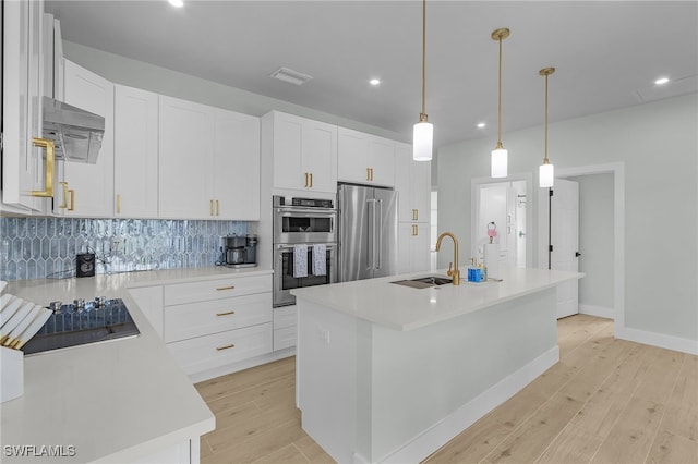 kitchen featuring appliances with stainless steel finishes, light wood-type flooring, a sink, and tasteful backsplash