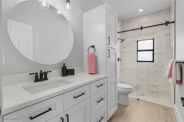 bathroom with a stall shower, vanity, toilet, and wood finished floors