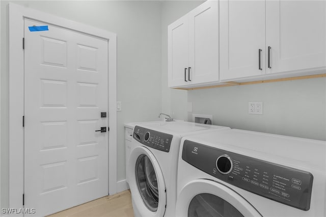 washroom featuring a sink, cabinet space, separate washer and dryer, and light wood finished floors