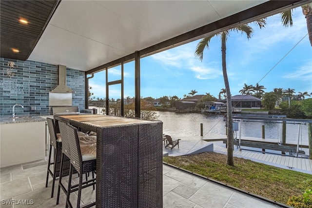 view of patio / terrace with a water view, a dock, outdoor dry bar, and a sink