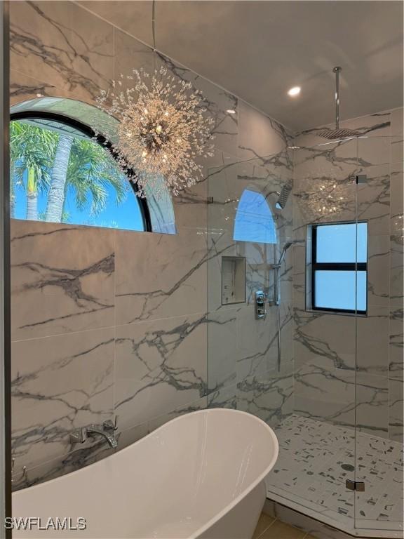 bathroom featuring a freestanding tub and a marble finish shower