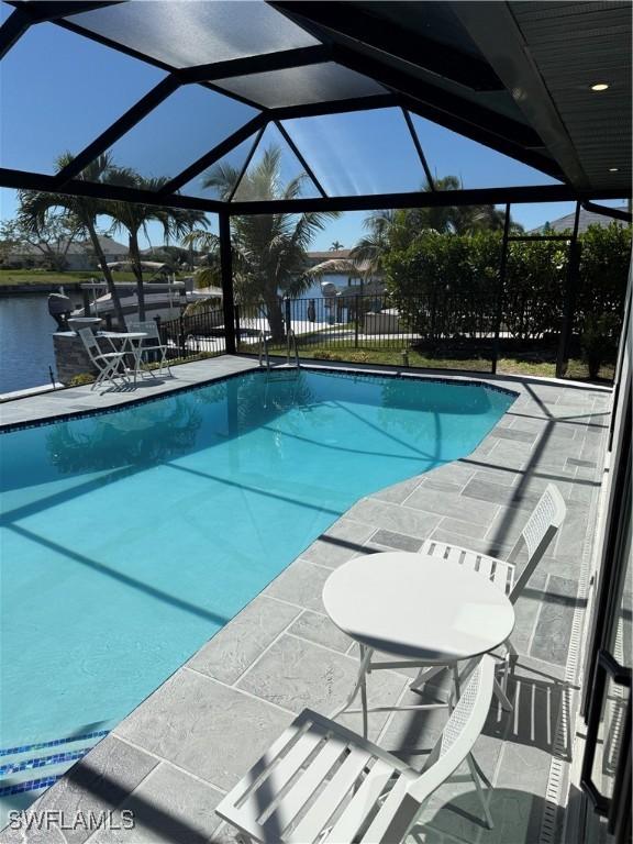 view of swimming pool featuring a fenced in pool, a patio, a water view, fence, and a lanai