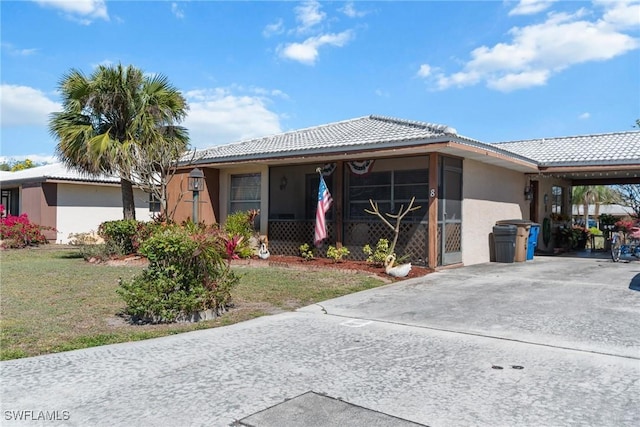 view of front of property featuring stucco siding, a tiled roof, concrete driveway, and a front yard