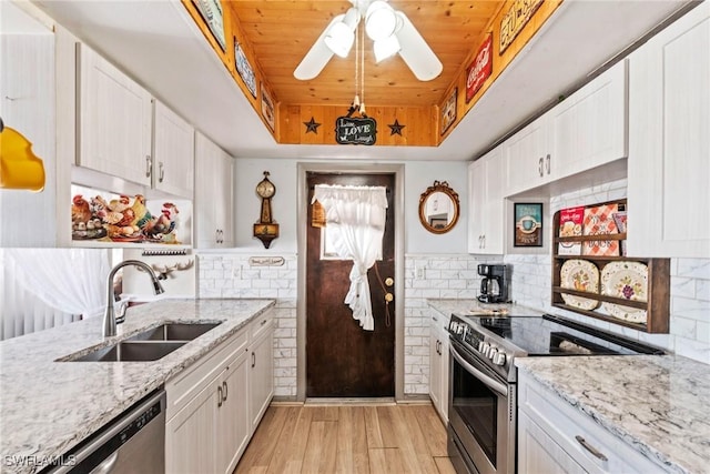 kitchen featuring light wood finished floors, wood ceiling, a tray ceiling, stainless steel appliances, and a sink