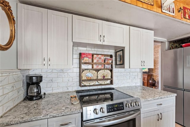 kitchen featuring light stone counters, stainless steel appliances, tasteful backsplash, and white cabinetry