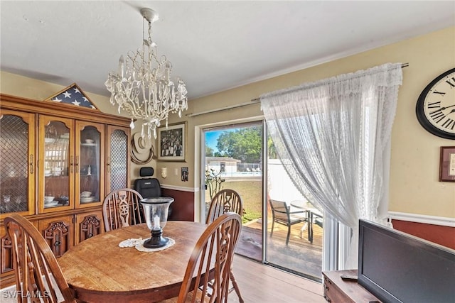 dining area with light wood-style floors and an inviting chandelier