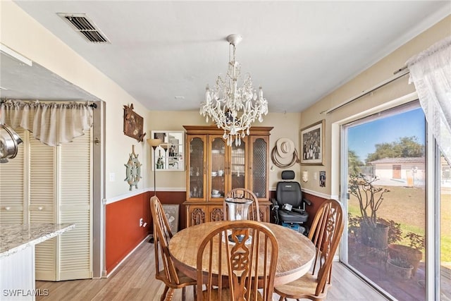 dining space featuring a notable chandelier, visible vents, and light wood finished floors