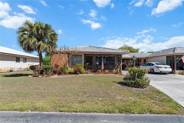 single story home with a front yard, a tile roof, and driveway