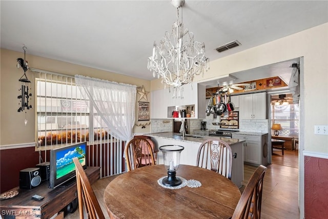 dining room with visible vents, wood finished floors, and ceiling fan with notable chandelier