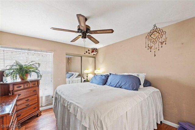 bedroom featuring a closet, baseboards, ceiling fan, and wood finished floors