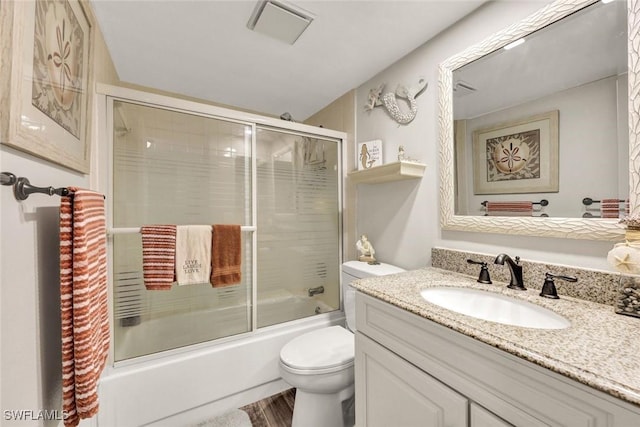 full bathroom with vanity, wood finished floors, visible vents, bath / shower combo with glass door, and toilet