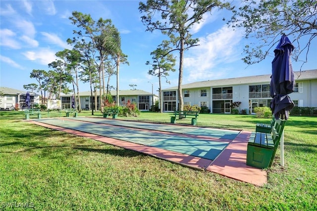 view of property's community with shuffleboard and a lawn