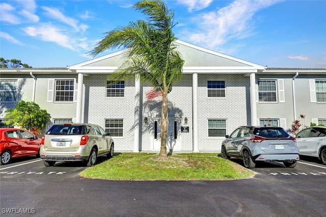 townhome / multi-family property featuring brick siding and uncovered parking