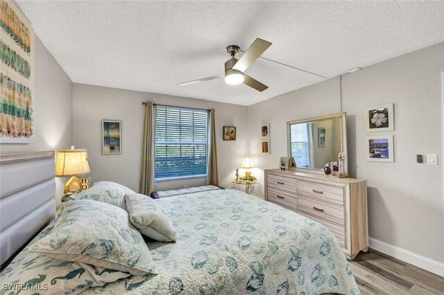 bedroom with baseboards, a textured ceiling, ceiling fan, and light wood finished floors