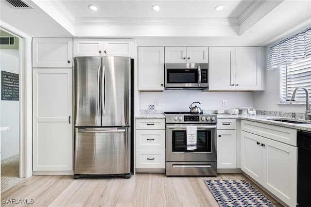 kitchen featuring visible vents, a sink, stainless steel appliances, white cabinets, and crown molding