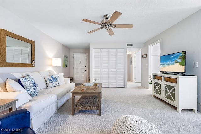 living area featuring a ceiling fan, visible vents, and light carpet