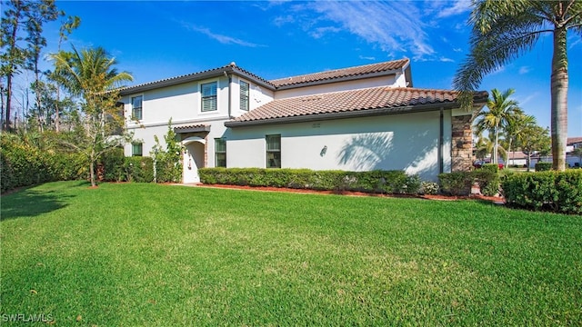 view of front of home featuring stucco siding, a tile roof, and a front yard