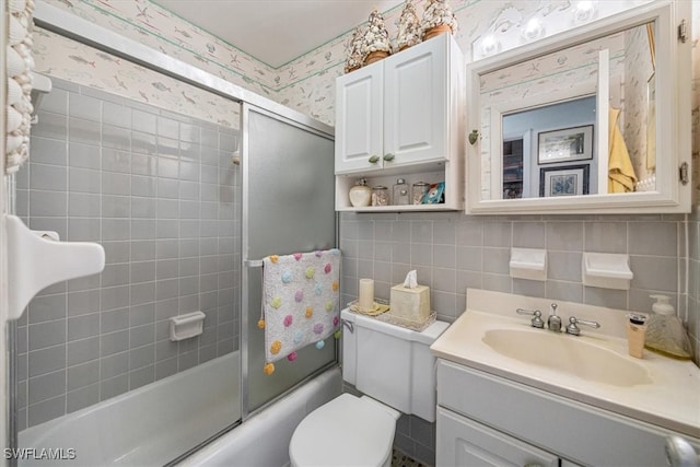 full bath featuring wallpapered walls, bath / shower combo with glass door, toilet, vanity, and tile walls