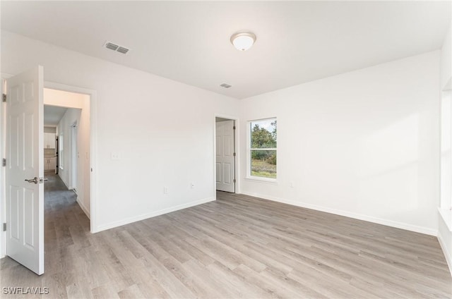 unfurnished room featuring visible vents, light wood-style flooring, and baseboards