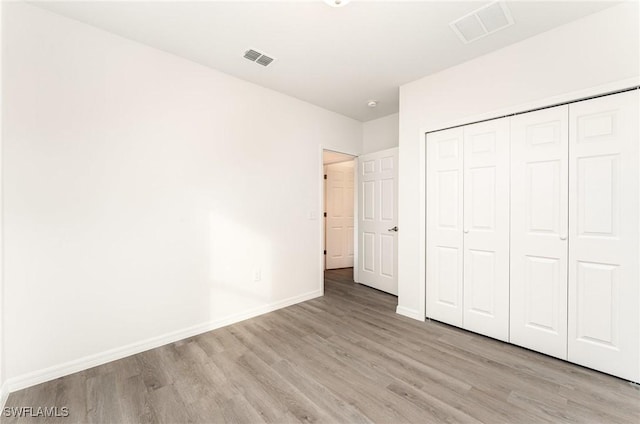 unfurnished bedroom with visible vents, baseboards, a closet, and wood finished floors