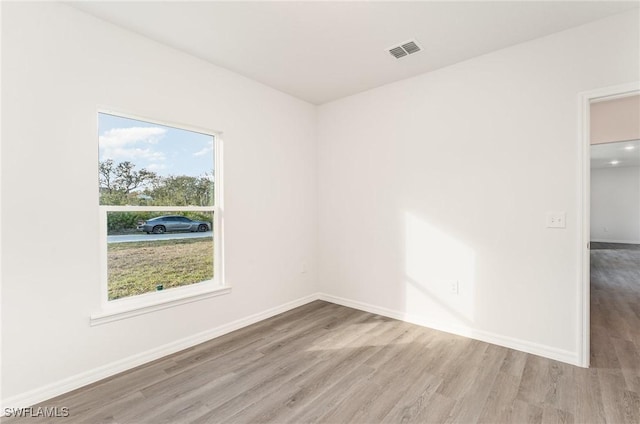 spare room featuring visible vents, baseboards, and wood finished floors