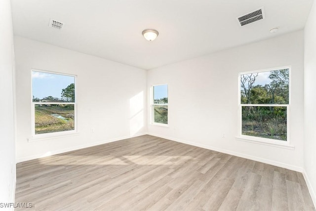 empty room with visible vents, baseboards, and light wood-style floors