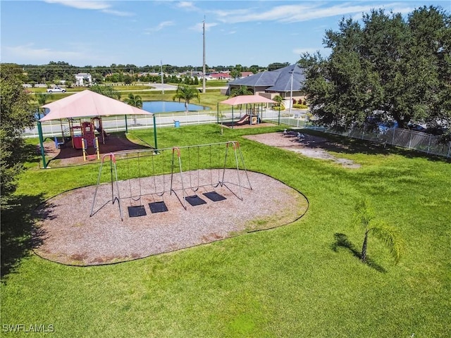 view of home's community with playground community, a water view, a lawn, and fence