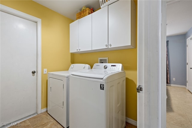 washroom with light tile patterned flooring, washing machine and dryer, cabinet space, and baseboards