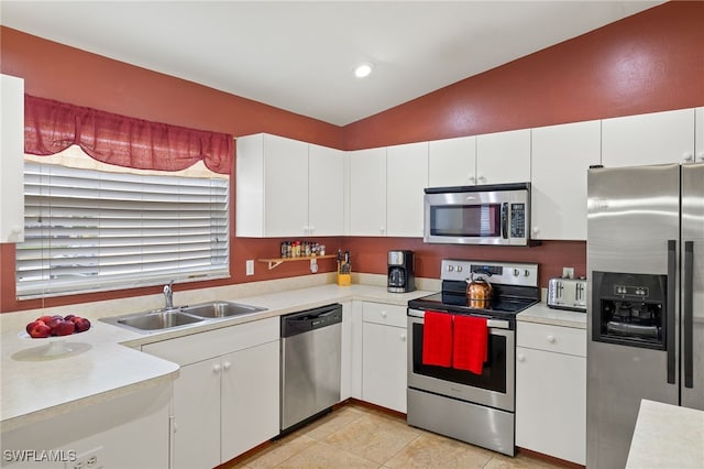 kitchen featuring stainless steel appliances, light countertops, lofted ceiling, and a sink