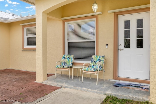 property entrance with stucco siding and a patio